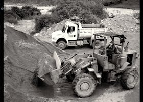 Excavator and dump truck working in a quarry on a clear day.